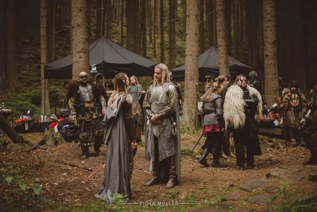 Plan filmowy LARP w lesie – aktorzy w zbrojach i szatach fantasy w tle z zapleczem technicznym