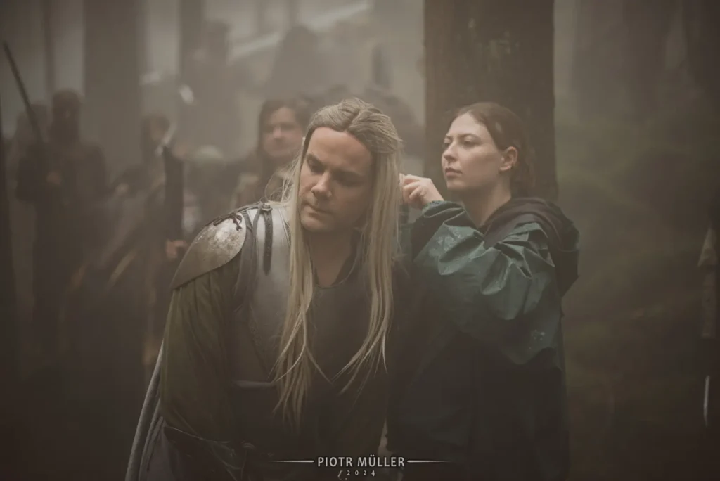 Aktor w zbroi i długich włosach fantasy przygotowywany do sceny przez ekipę filmową